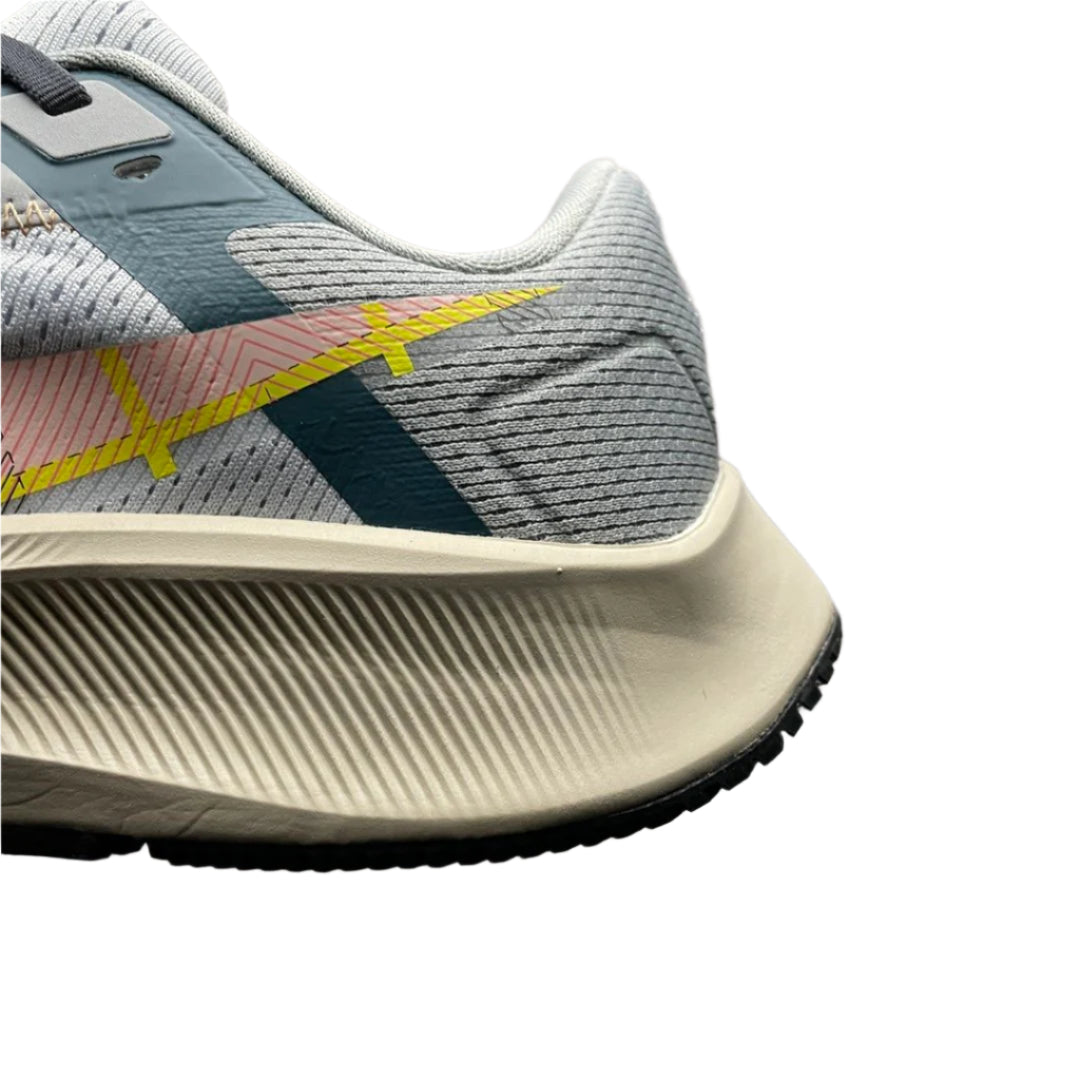 Close-up of a gray athletic shoe with yellow accents on a textured black surface