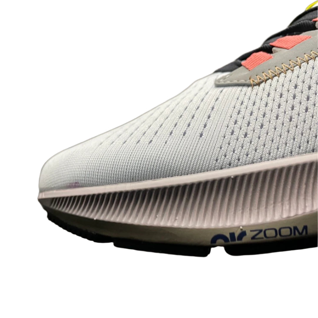 Close-up of a gray running shoe with 'Zoom' branding on a textured surface